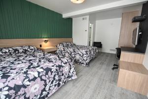a hotel room with two beds and a flat screen tv at Motel Blanche d'Haberville in Saint-Jean-Port-Joli