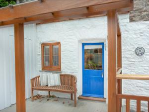 a bench sitting on a porch with a blue door at Tuckenhay, 1 Castle Cottage - Fck in Ashsprington