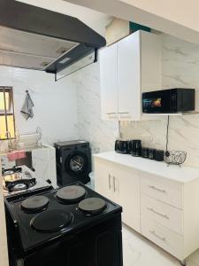 a kitchen with a black stove and white cabinets at Elvara's Nest in Lusaka