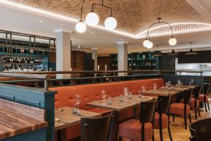 a restaurant with wooden tables and chairs and lights at The Malone Hotel in Belfast