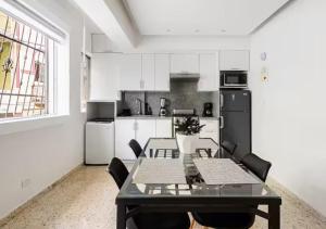 a dining room with a table and a kitchen with white cabinets at Colonial Zone 2BR Apartment Prime Location in Santo Domingo