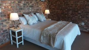 a bedroom with a bed with a brick wall at Dolphin Villa in Gqeberha