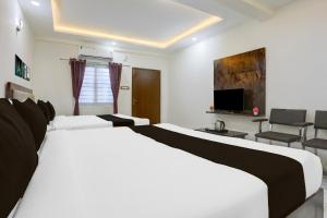 a hotel room with two beds and a television at Hotel O Aqua Comforts in Yelahanka