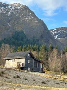 a small house on a hill with mountains in the background at Deer Cottage in Sylte