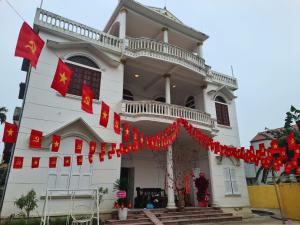a white building with red flags in front of it at Snow Homestay in Ninh Binh