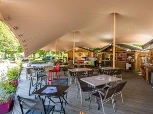 a restaurant with tables and chairs under a tent at Flower Camping Le Pont du Tarn in Florac