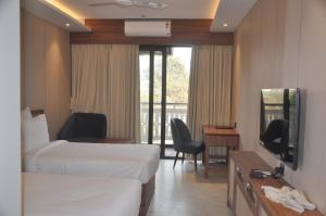 a hotel room with two beds and a television at Pahadi Convention in Rourkela