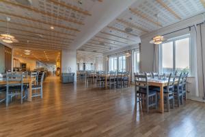 a dining room with tables and chairs and large windows at Åh Stifts- & Konferensgård in Ljungskile