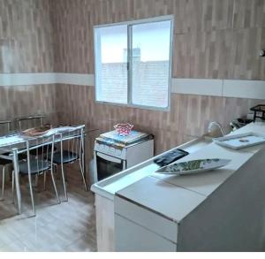 a kitchen with a counter and a table and a window at Casa independente e espaçosa em Poços de caldas in Poços de Caldas