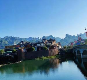 a bridge over a river with houses and a bridge at Zhangjiajie Gui Yuan Hotel - Free delivery to the East Gate once--service washing machine with drying, luggage storage-over 4 nights and get one free airport pick-up in Zhangjiajie