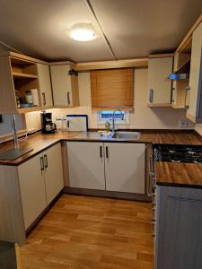 a kitchen with white cabinets and a sink at Cozy corner house, New vennepark in De Haan