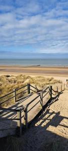 a wooden bench sitting on a sandy beach at Cozy corner house, New vennepark in De Haan