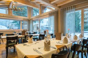 a dining room with tables and chairs and windows at Hotel Jägerhof in Zermatt