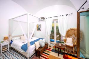 a bedroom with a canopy bed and a chair at Luxury Maison Cherie - Positano Charme & Sea View in Positano