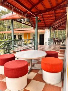 a patio with red and white tables and stools at Malnad Mist in Attigundi