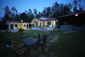 a house with a table and chairs in the yard at Malnad Mist in Attigundi