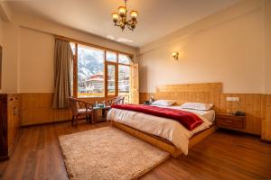 a bedroom with a bed and a desk and a window at Jawai Himalayan Cottage in Vashisht