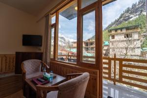 a room with a table and chairs and a large window at Jawai Himalayan Cottage in Vashisht