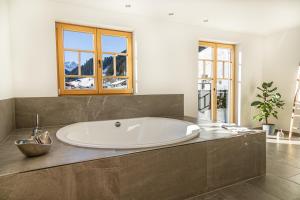 a large white tub in a bathroom with windows at Chalet Zaferna in Mittelberg