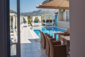 a swimming pool with chairs and a table and an umbrella at Cloud9 Hotel Shisha & Cocktail Bar - Adults Only in Malia