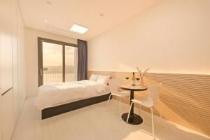 a bedroom with a bed and a table and a window at World Sky Residence Hotel in Sokcho