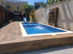 a swimming pool with a water fountain at Casa Com Jacuzzy aquecida e Piscina próx a praia ideal para famílias e casais in Caraguatatuba