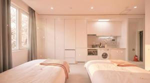 two beds in a room with a kitchen at World Sky Residence Hotel in Sokcho