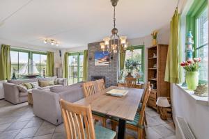 a kitchen and living room with a wooden table and chairs at Vakantiehuis Miriam op park Strandslag Julianadorp aan Zee in Julianadorp +28 photos