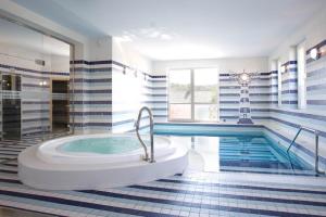 ein großes Badezimmer mit Badewanne und Swimmingpool in der Unterkunft Hotel Dakol in Petrovice u Karviné