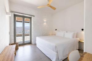 a white bedroom with a bed and a large window at Lithi House in Grionísi +24 photos