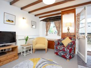 a living room with a tv and a chair at Tuckenhay, 2 Castle Cottage - Fcl in Ashsprington