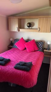 a bedroom with a pink bed with pink pillows at 107 Arran View with WiFi in Ayr