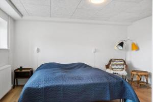 a bedroom with a blue bed and a chair at 717-Thyboron-Jernbanegade-3 in Thyborøn