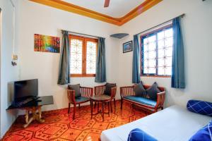 a bedroom with a bed and chairs and a tv at Anjuna Beach House in Anjuna