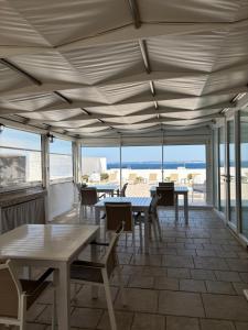 a patio with tables and chairs and a view of the ocean at Faro Bianco Gallipoli - Suites & Apartments in Gallipoli