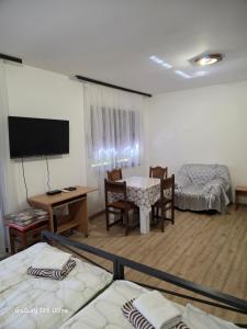 a room with two beds and a table and a tv at Sobe IVANA in Gornja Toplica