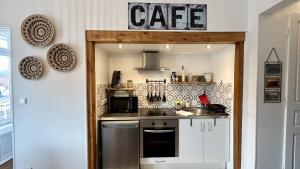 a kitchen with white cabinets and a sign that reads cafe at Belle échappée in Le Crotoy