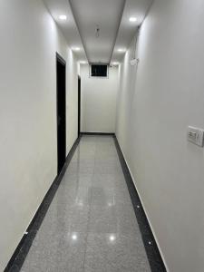 an empty hallway with a black door and a white wall at Hotel Grand Father in Agra