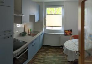 a kitchen with white cabinets and a window and a table at Apfelhof Rüdersdorf in Rüdersdorf +3 photos