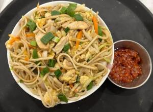 a plate of food with noodles and a bowl of sauce at Hotel BR international in Tājganj