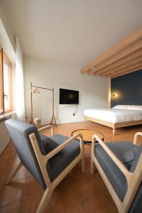 a bedroom with a bed and two chairs and a tv at B&B Il Faggio Rosso in Vernante