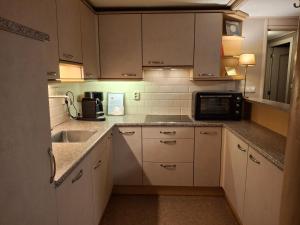 a kitchen with white cabinets and a sink and a microwave at De Galeriet Giethoorn in Giethoorn +21 photos