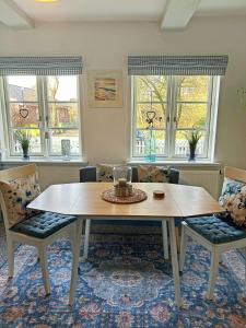 a dining room with a table and chairs and windows at Pastor's Stuv Das Alte Pastorat in Uelvesbüll