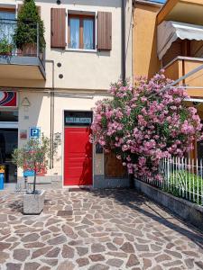 a building with a red door and flowers in front of it at Camera Lucy in Bardolino