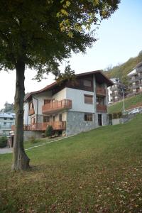 a building on a hill with a tree in the foreground at B&B Il Faggio Rosso in Vernante