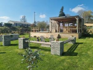 a house with a bench in the grass at Tiny housse serenity avec jacuzzi et piscine in Tinlot