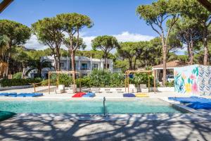 a swimming pool with a pool noodle park and trees at Hotel New Barcavela in Santa Margherita di Pula
