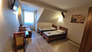 a room with two beds and a table and a window at Noclegi Tyczyn in Tyczyn