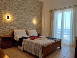 a bedroom with a bed with a brick wall at Corali Hotel in Piso Livadi