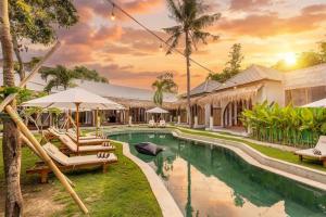 an image of a resort pool with chairs and umbrellas at Roh Villas Kuta Lombok in Kuta Lombok